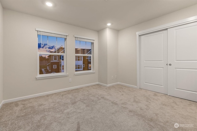 unfurnished bedroom featuring light colored carpet and a closet