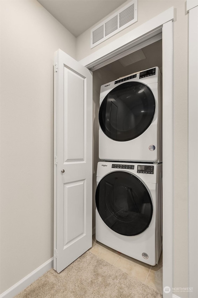 washroom featuring light tile patterned floors and stacked washer and clothes dryer