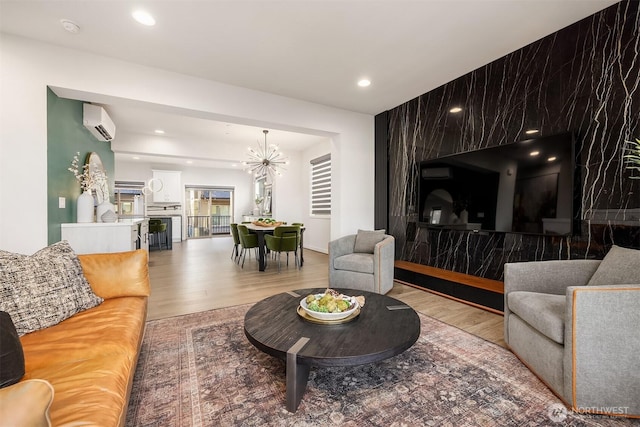 living room with a notable chandelier, recessed lighting, a wall mounted AC, an accent wall, and wood finished floors