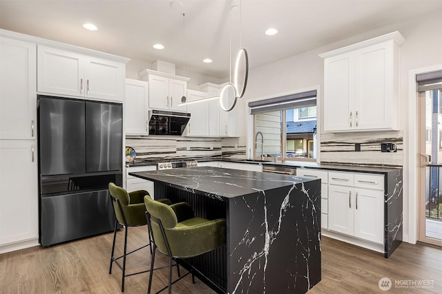 kitchen with a center island, wood finished floors, white cabinetry, and stainless steel refrigerator