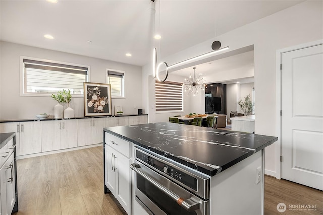 kitchen featuring dark countertops, light wood finished floors, white cabinets, and recessed lighting