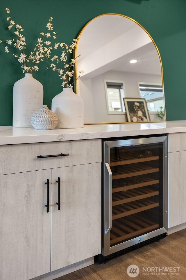 bar with wine cooler, dark wood-style flooring, and a bar