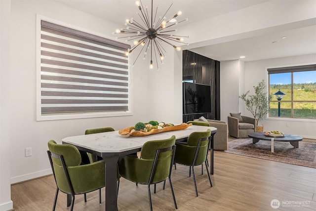 dining area featuring an inviting chandelier, light wood-style flooring, and baseboards