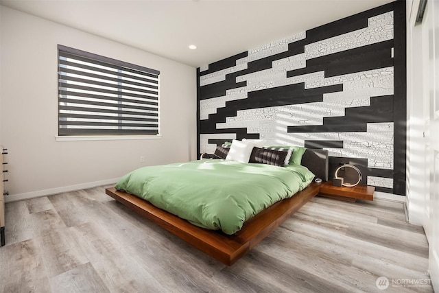 bedroom featuring an accent wall, recessed lighting, wood finished floors, and baseboards