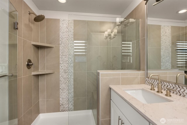 full bathroom with a stall shower, backsplash, tile walls, and vanity