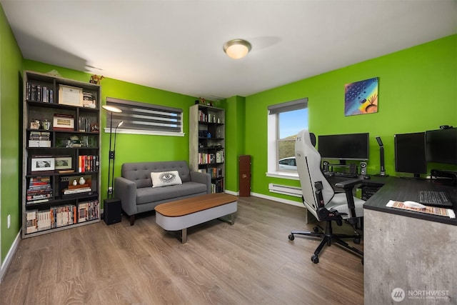 office space featuring baseboards, a baseboard heating unit, and wood finished floors