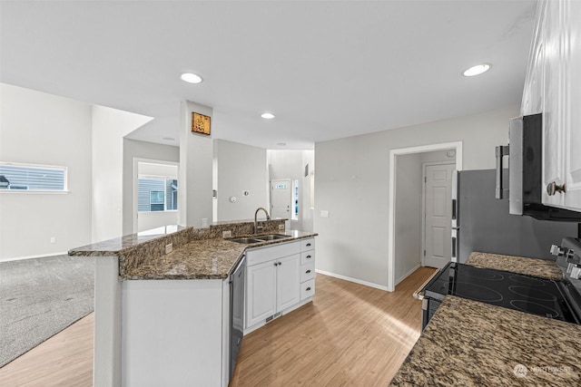 kitchen with white cabinetry, sink, dark stone counters, light hardwood / wood-style floors, and stainless steel appliances