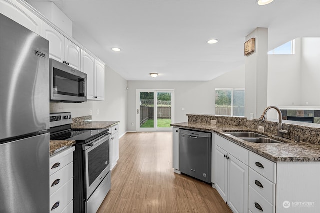 kitchen with white cabinetry, stainless steel appliances, sink, and dark stone countertops