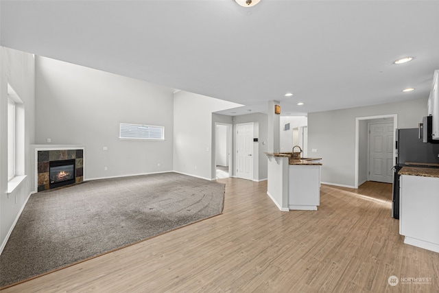 unfurnished living room with light hardwood / wood-style flooring, sink, and a fireplace