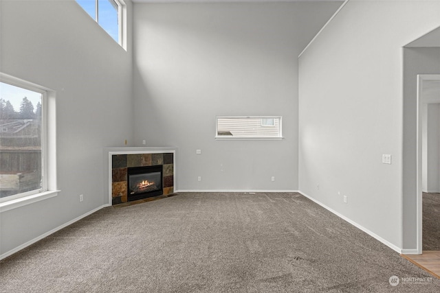 unfurnished living room featuring carpet, a towering ceiling, and a fireplace