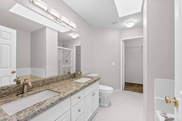 full bathroom with vanity, a skylight, independent shower and bath, and toilet