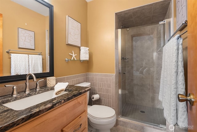 bathroom featuring a stall shower, toilet, and tile walls