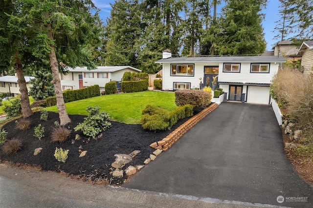 raised ranch featuring a garage and a front yard