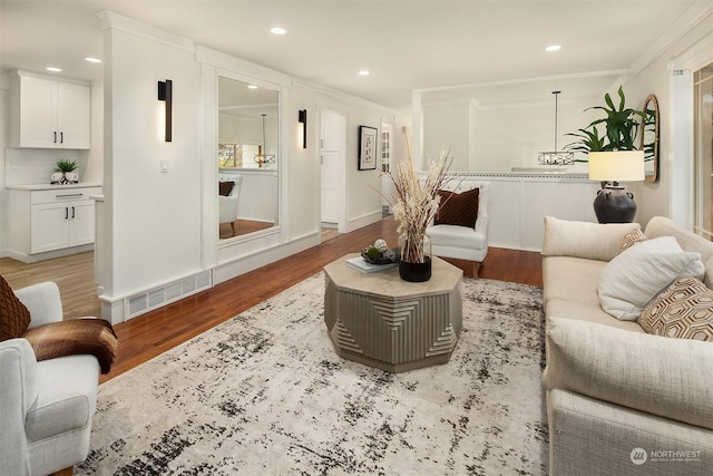 living room with ornamental molding and light hardwood / wood-style flooring