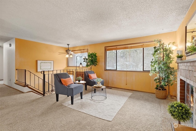 sitting room with ceiling fan, a fireplace, a textured ceiling, and carpet flooring