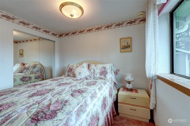 carpeted bedroom featuring a textured ceiling and a closet