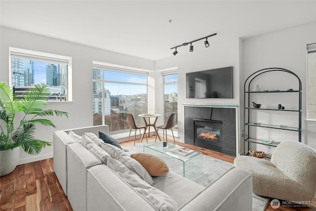 living area with track lighting, baseboards, wood finished floors, and a tile fireplace