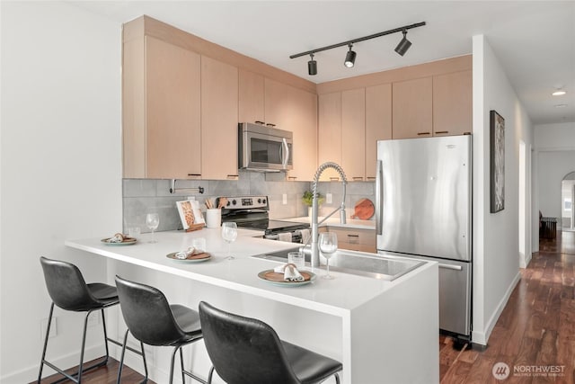 kitchen with arched walkways, stainless steel appliances, light countertops, decorative backsplash, and a peninsula