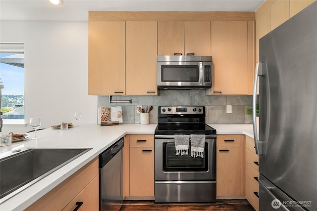 kitchen featuring stainless steel appliances, tasteful backsplash, light countertops, and light brown cabinetry