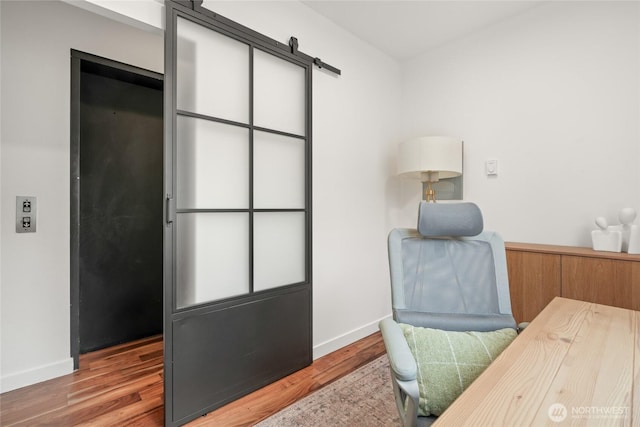 office space with wood finished floors, baseboards, and a barn door