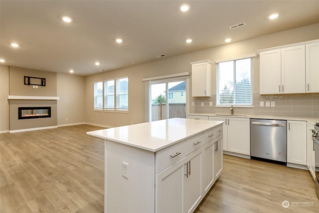 kitchen with dishwasher, sink, white cabinets, backsplash, and a center island