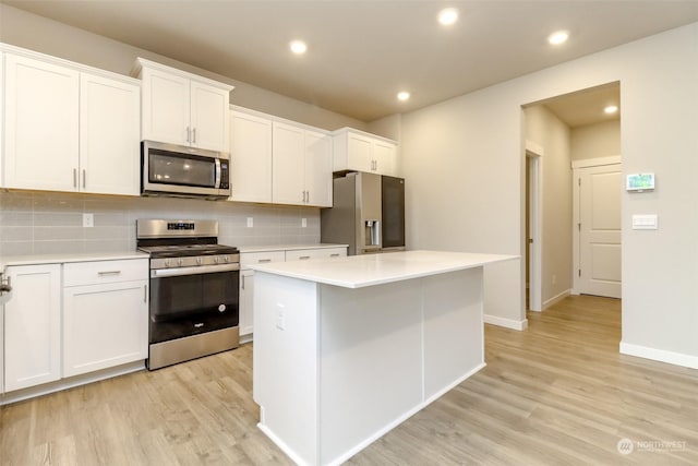 kitchen featuring backsplash, stainless steel appliances, a center island, light hardwood / wood-style floors, and white cabinets