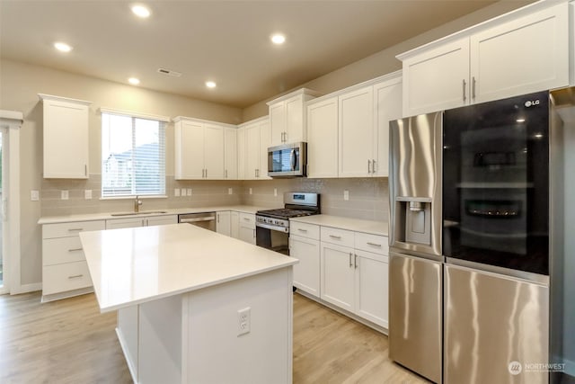 kitchen featuring sink, a kitchen island, white cabinets, and appliances with stainless steel finishes