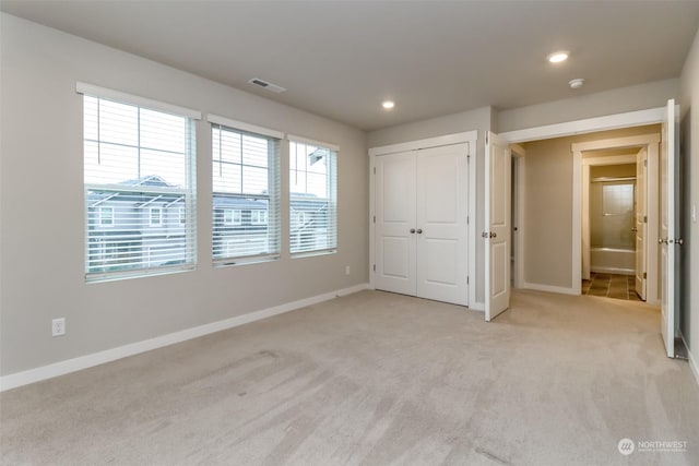 unfurnished bedroom featuring light carpet and a closet