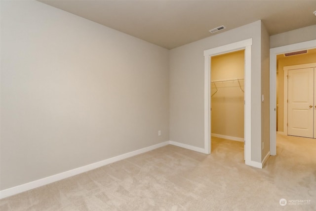 unfurnished bedroom with light colored carpet, a closet, and a walk in closet