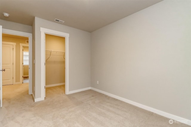 unfurnished bedroom with light carpet, a spacious closet, and a closet