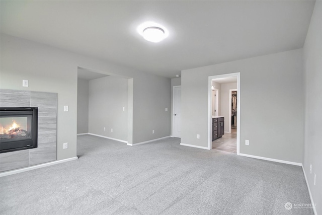 unfurnished living room with a tile fireplace and light colored carpet