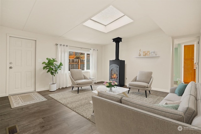 living room featuring wood-type flooring, a wood stove, and a skylight