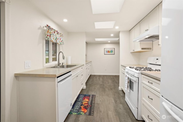 kitchen with dark wood-type flooring, sink, a skylight, white appliances, and white cabinets