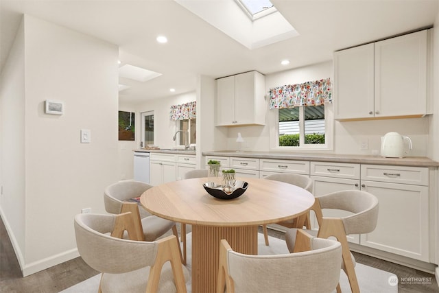 dining room with hardwood / wood-style flooring, sink, and a skylight