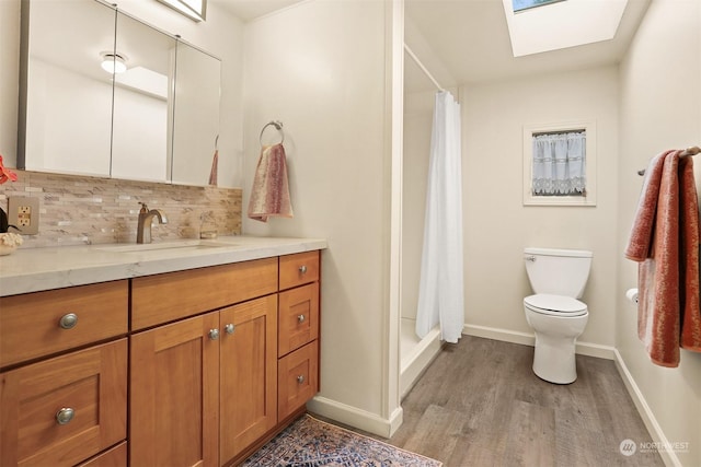 bathroom featuring walk in shower, vanity, a skylight, and decorative backsplash