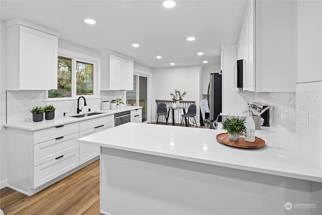 kitchen featuring white cabinetry, sink, light hardwood / wood-style floors, and appliances with stainless steel finishes