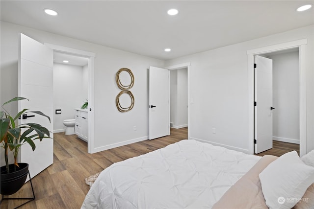 bedroom with hardwood / wood-style floors and ensuite bath