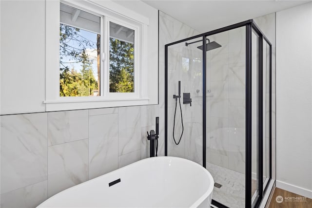 bathroom with shower with separate bathtub, wood-type flooring, and tile walls