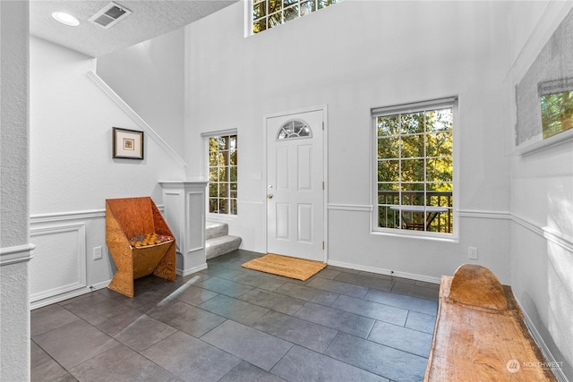 foyer entrance featuring a towering ceiling, a healthy amount of sunlight, and a textured ceiling