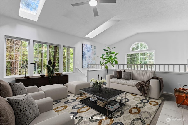 living room with ceiling fan, lofted ceiling with skylight, a textured ceiling, and light tile patterned floors