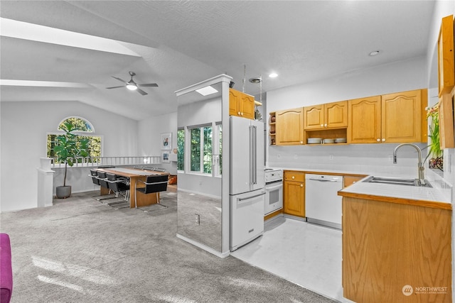 kitchen featuring sink, white appliances, hanging light fixtures, tile counters, and vaulted ceiling