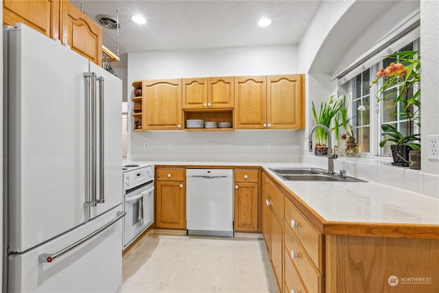 kitchen featuring sink, tile countertops, a textured ceiling, kitchen peninsula, and white appliances