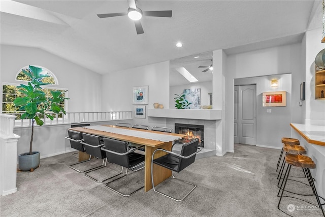 playroom with ceiling fan, lofted ceiling, a tiled fireplace, and light carpet