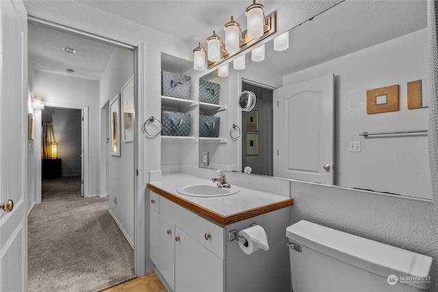 bathroom featuring vanity, toilet, and a textured ceiling