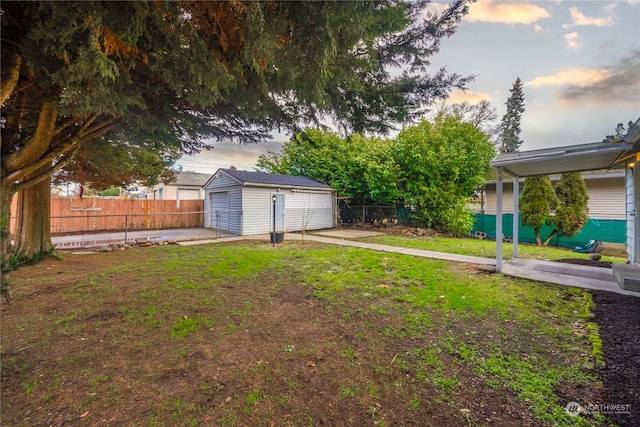 yard at dusk featuring an outbuilding and a garage