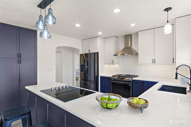 kitchen with black appliances, sink, hanging light fixtures, and wall chimney range hood