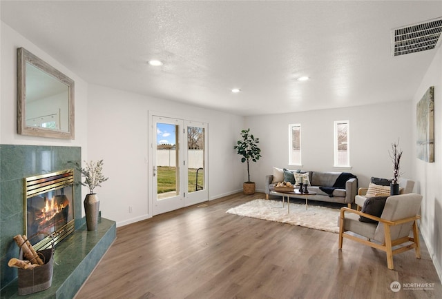 living room featuring dark hardwood / wood-style flooring, a tile fireplace, and a textured ceiling