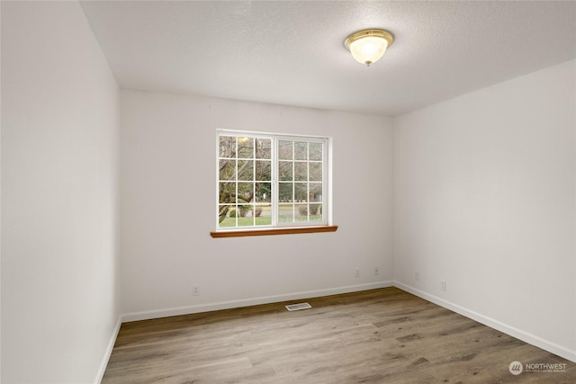 spare room featuring hardwood / wood-style floors and a textured ceiling