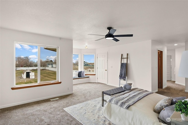 carpeted bedroom featuring ceiling fan and a textured ceiling