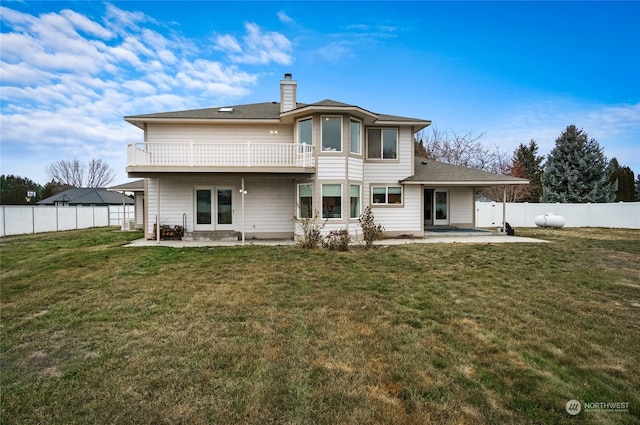 rear view of house with a balcony, a lawn, and a patio area